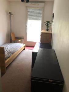 Un dormitorio con una cama y un escritorio y una ventana. en BEL ET SPACIEUX APPARTEMENT AVEC TERRASSES ET JARDINS EN RDC / COUR PROCHE RER B ET TRAM BANLIEUE PARIS SUD, en Châtenay-Malabry