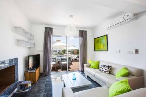 a living room with a couch and a tv at Villa Indigo Paphos in Paphos City