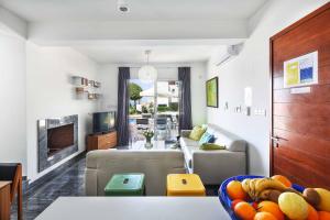 a living room with a couch and a table with a bowl of fruit at Villa Indigo Paphos in Paphos City