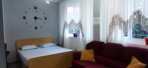 Habitación con sofá, cama y reloj en LEVI Apartment, en Pogradec