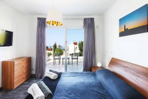 a bedroom with a blue bed and a large window at Villa Indigo Paphos in Paphos City +9 photos