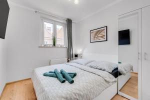 een witte slaapkamer met een bed met blauwe voorwerpen erop bij Apartamenty Franciszkańska in Opole