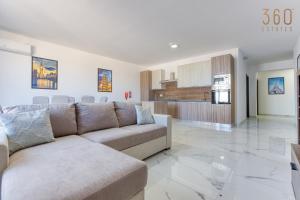 ein Wohnzimmer mit einem Sofa und einer Küche in der Unterkunft One of a kind 4BR penthouse with terrace & views by 360 Estates in St Paul's Bay