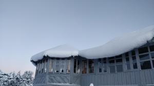 a building covered in snow on the roof at Black Bear Cottage khajjiar in Khajjiar 