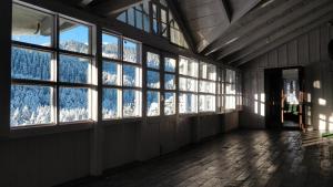 an empty room with windows and snow covered mountains at Black Bear Cottage khajjiar in Khajjiar 