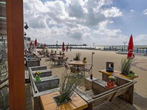 een patio met tafels en stoelen op het strand bij Spacious bungalow with roofed terrace 