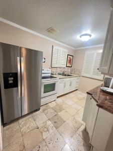 La cuisine est équipée d'un réfrigérateur en acier inoxydable et de placards blancs. dans l'établissement A Cottage in Tropical Paradise, à Waimanalo
