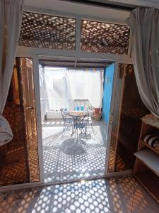 Habitación con mesa y puerta de cristal en CampSurf Morocco, en Tamraght Ouzdar