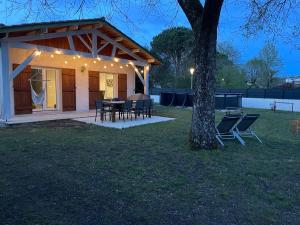 une maison avec une table, des chaises et un arbre dans l'établissement Villa au calme avec piscine, grand jardin et studio indépendant, à Andernos-les-Bains