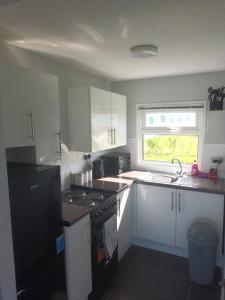 a kitchen with white cabinets and a black stove top oven at Collier's Corner Chalet California Sands Scratby Great Yarmouth in Scratby