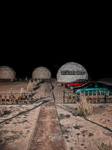 kilka samochodów zaparkowanych przed namiotami w obiekcie Rum Lucille Luxury camp w mieście Wadi Rum