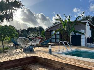 a wooden deck with chairs and a swimming pool at Los Dos Caballeros Winery & Vacation Rental in Llubí