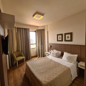 Habitación de hotel con cama y silla en L'Hirondelle Flat Service en Campinas