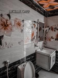 a bathroom with a sink and a toilet with flowers on the wall at RUM LUCILLE lUXURY CAMP in Wadi Rum +28 photos