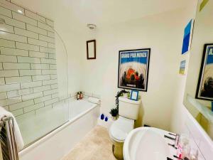 a bathroom with a toilet and a tub and a sink at Spacious City Centre Apartment Bath in Bath