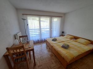 1 dormitorio con cama, escritorio y ventana en Tariche Centre de Vacances en Saint-Ursanne