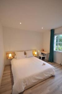 Un dormitorio con una gran cama blanca y una mesa en villa chanoine poupard, en Nantes