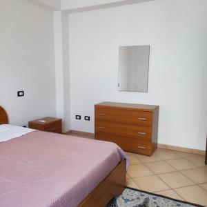 een slaapkamer met een bed en een houten dressoir bij La casa di Andrea in Terrasini