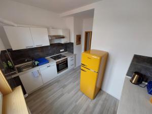 uma cozinha com um frigorífico amarelo e armários brancos em FEWO SALENBERG em Freudenstadt
