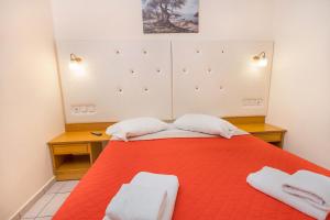 a bedroom with a red bed with two white towels at Eri Beach & Village Hotel in Hersonissos