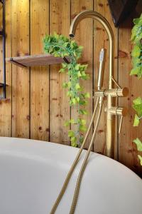 a bath tub with a faucet next to a wooden wall at Little Paddock in Ringwood