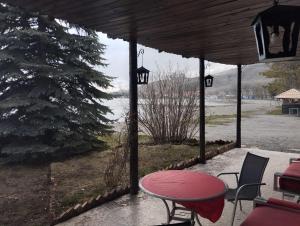 un patio con una mesa roja, sillas y un árbol en Севан 3 Ветерок en Sevan