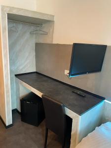 einen Schreibtisch mit einem TV darüber in einem Zimmer in der Unterkunft Etna Hotel & Ristorante in Veitshöchheim