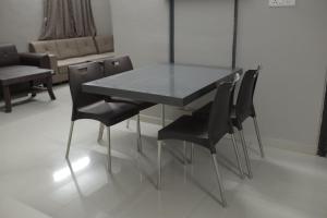 a dining room table with black chairs and a couch at Kookee Villa in Hātgarh