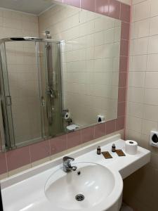 een badkamer met een wastafel, een douche en een spiegel bij Hotel Domino in Głubczyce