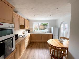 a kitchen with wooden cabinets and a wooden table with a tableablish at Bilbo's Cottage, Sheringham in Sheringham