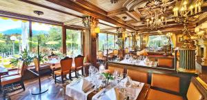 um restaurante com mesas e cadeiras brancas e janelas em Hotel Schloss Fernsteinsee em Nassereith