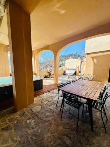 un patio con mesa de madera y sillas en un edificio en Authentique appartement vue montagnes avec grand patio et jacuzzi chauffé, en Santa-Reparata-di-Balagna