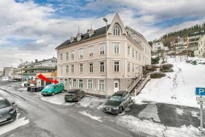 a large building with cars parked in the snow at Central 1BR Apartment in Narvik