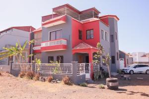a red and gray house with a car parked in front at Escape House in Tarrafal