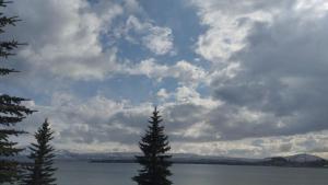 um céu nublado com duas árvores em frente a um lago em Севан 3 Ветерок em Sevan