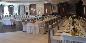 un salón de banquetes con mesas y sillas blancas y registrador en Hotel Domino en Głubczyce