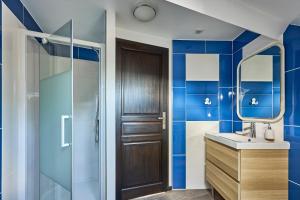 a bathroom with blue tiled walls and a wooden door at Ethoucky - Maison à 300m de la plage in Bernières-sur-Mer +6 photos