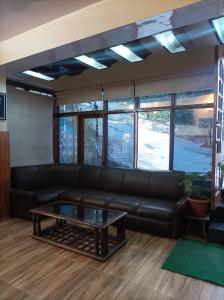 a living room with a leather couch and a coffee table at Hotel Rajat in Shimla
