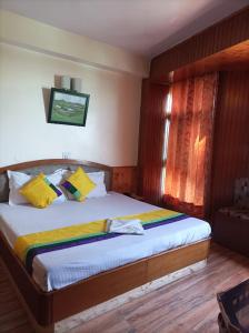 a bedroom with a large bed with yellow pillows at Hotel Rajat in Shimla