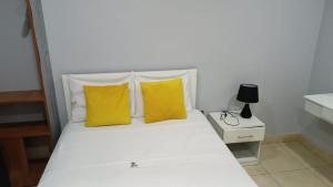 sypialnia z białym łóżkiem z żółtymi poduszkami w obiekcie RentvistaVerde w mieście Tarapoto