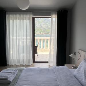 a bedroom with a bed and a large window at Turquoise Beachside Apartments in Dobrota