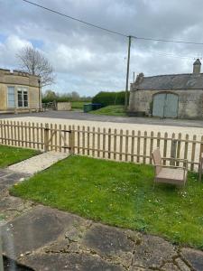 a bench sitting in the grass next to a fence at Pretty cottage near Cirencester in Purton