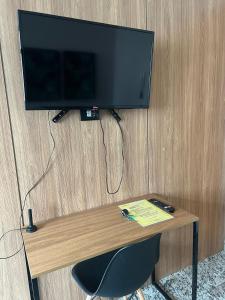 a television on a wall with a chair under a table at Locking's Lourdes 3 in Belo Horizonte