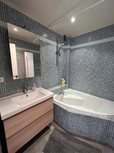 een badkamer met een bad, een wastafel en een spiegel bij Appartement Unique - Roucas Blanc in Marseille