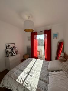 1 dormitorio con 1 cama con cortinas rojas y ventana en Appartement Unique - Roucas Blanc en Marsella