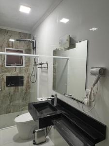 a bathroom with a sink and a toilet and a mirror at Hotel Araçariguama in Araçariguama