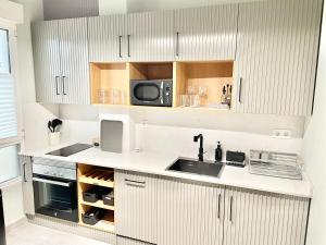 a kitchen with white cabinets and a sink and a microwave at Estudio Regenta Con Parking privado in Oviedo