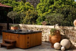 a hot tub in a garden with a stone wall at Villa Fluvian in Rhodes Town