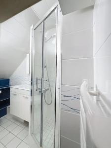 La salle de bains blanche est pourvue d'une douche et d'un lavabo. dans l'établissement La Fraisnaie YourHostHelper, à Saint-Laurent-sur-Mer