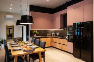 a kitchen with a dining table and a kitchen with pink walls at Villa Fluvian in Rhodes Town
